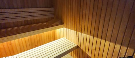 A sauna with wooden benches and a bench with a backrest.