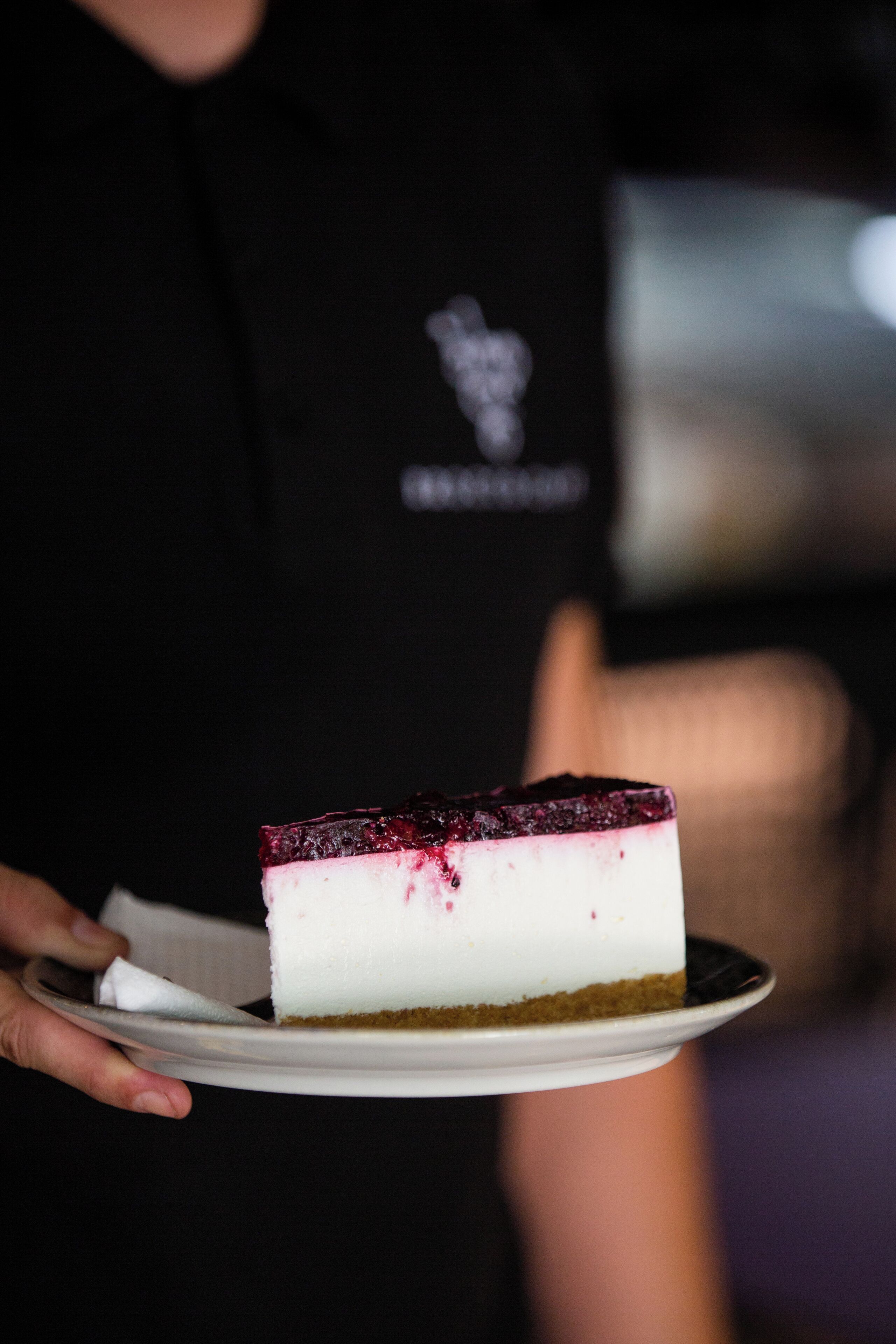 A slice of cheesecake with a berry topping on a white plate.