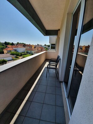 A balcony with a view of neighboring houses, a small table, and a chair. - Hotel Brotnjo (Citluk)