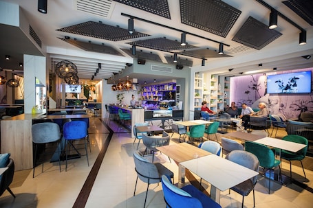 A modern restaurant with a bar area, seating, and a TV screen displaying a program.