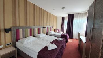 A hotel room with two beds, a desk, and a wardrobe.