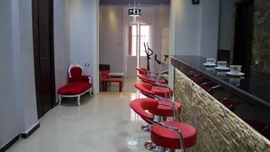 Un hall d’hôtel avec un long comptoir d’accueil, des chaises rouges et un mur en pierre.