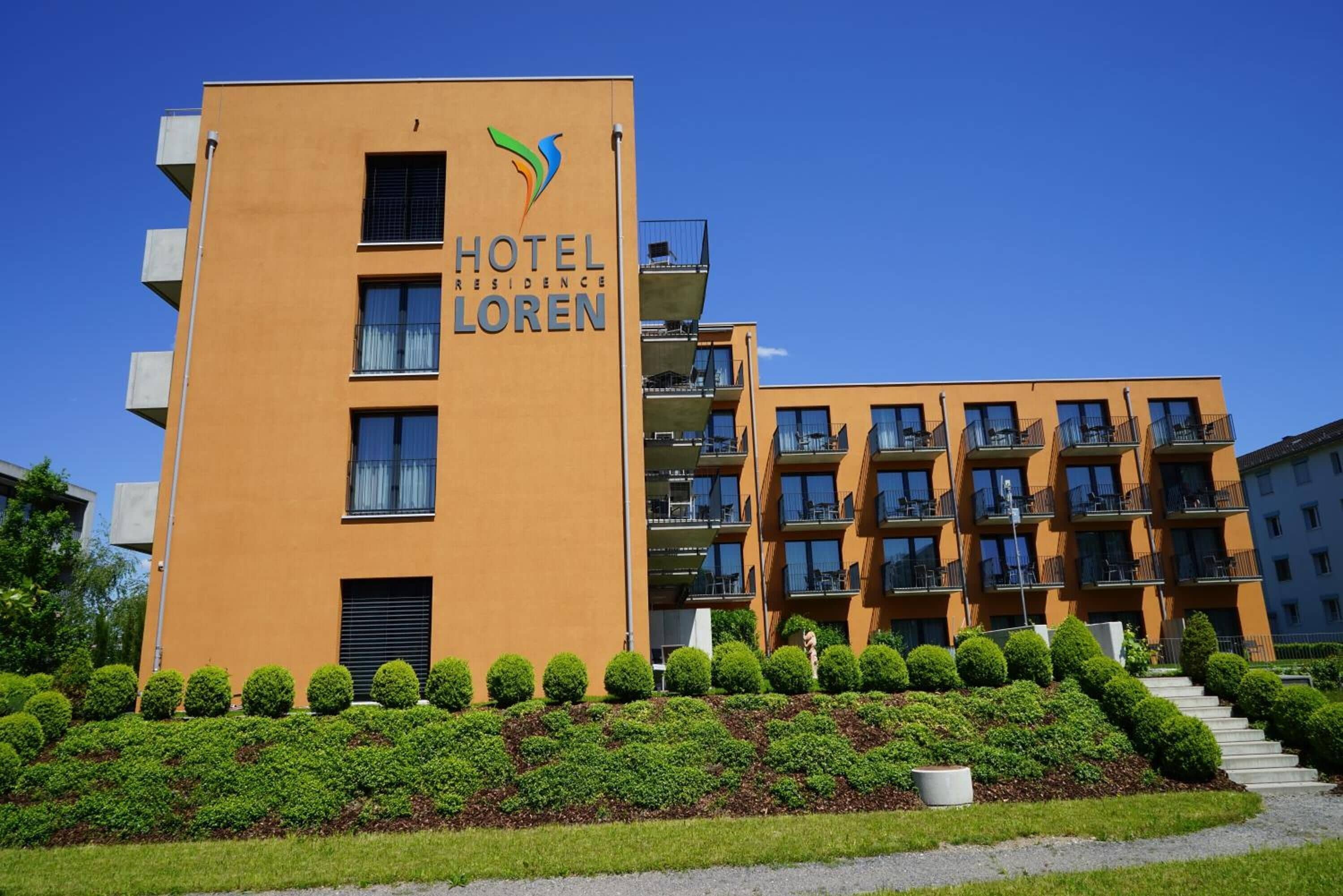 A modern hotel building with a prominent sign reading "HOTEL RESIDENCE LOREN".