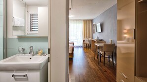 Una habitación de hotel con baño, zona de comedor y sala de estar.