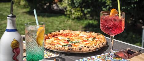 A pizza on a table with a drink and snacks.