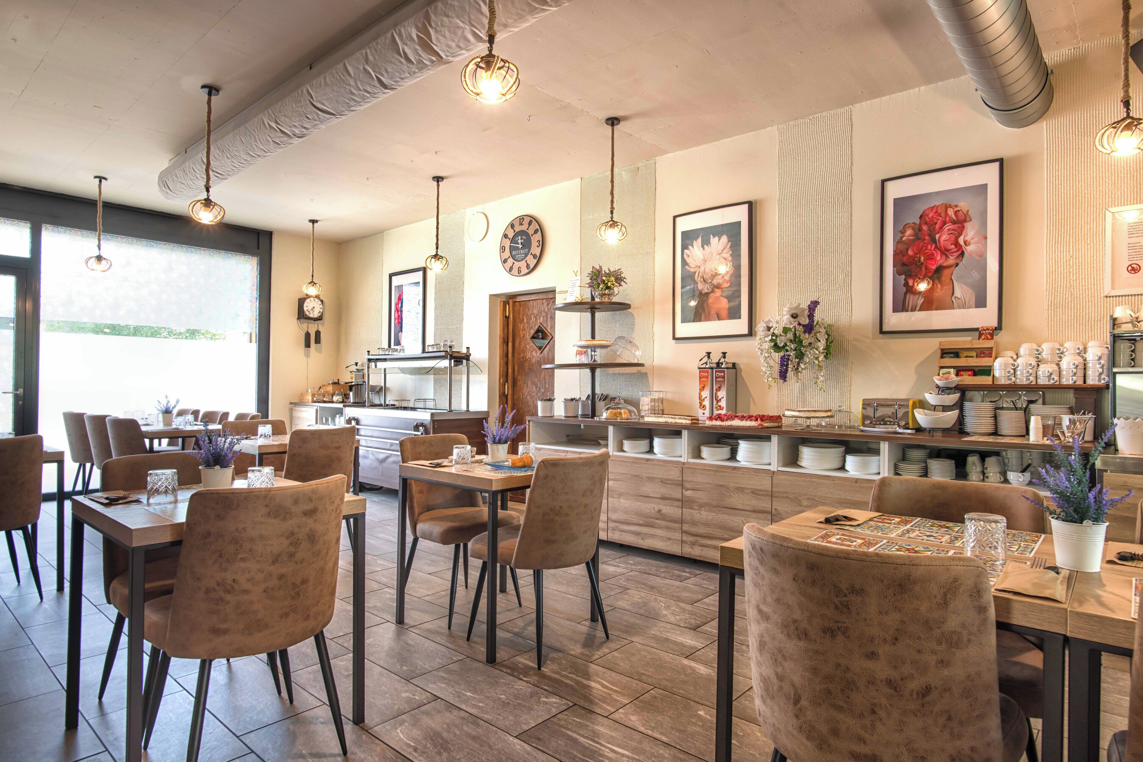 Un restaurant moderne doté d’une salle à manger centrale, d’une cuisine située à l’arrière et d’un bar avec des étagères remplies d’assiettes.
