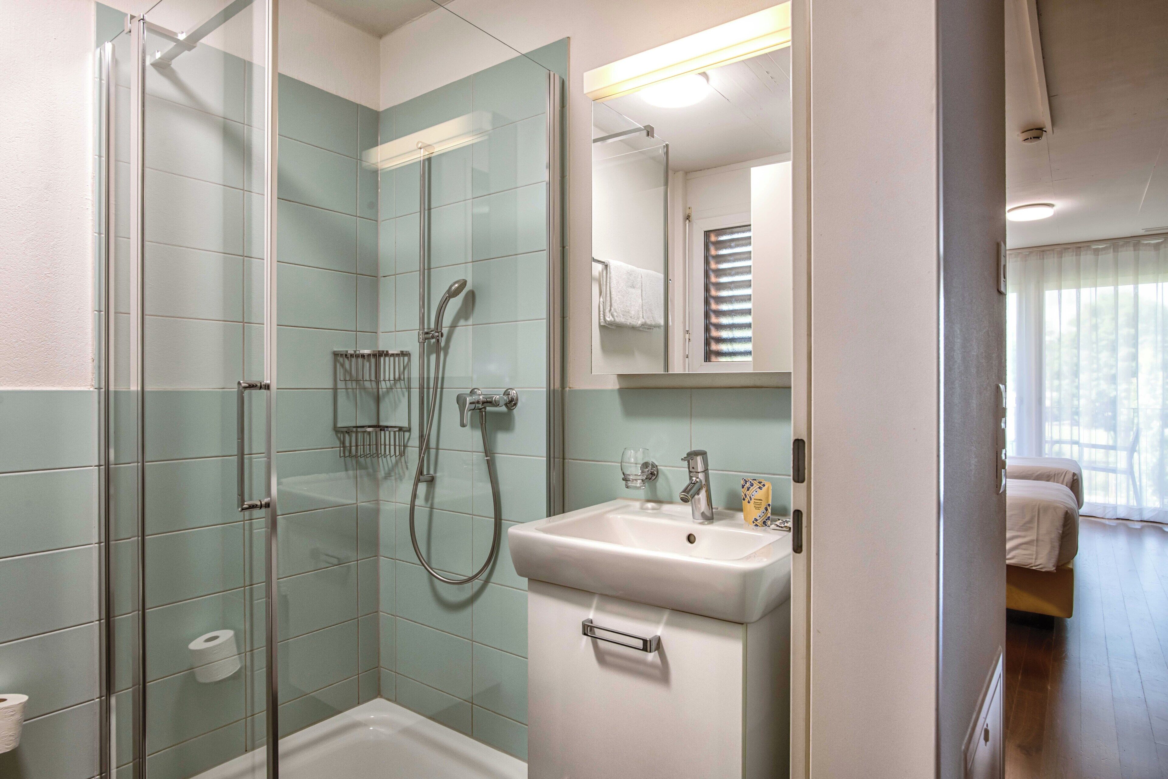 A bathroom with a glass-enclosed shower, a sink, and a mirror.