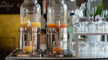 Two glass dispensers with orange juice, a tray with empty glasses, and a sign in the background.