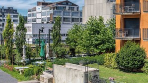 Zona residencial urbana moderna con edificios de varios pisos, mobiliario exterior y áreas verdes.