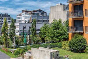 Zona residencial urbana moderna con edificios de varios pisos, mobiliario exterior y áreas verdes.