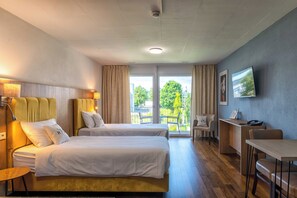 Quarto de hotel com duas camas, uma escrivaninha, uma cadeira e uma televisão.