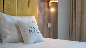 A bed with a white pillow featuring a colorful logo and the letters "HHL".