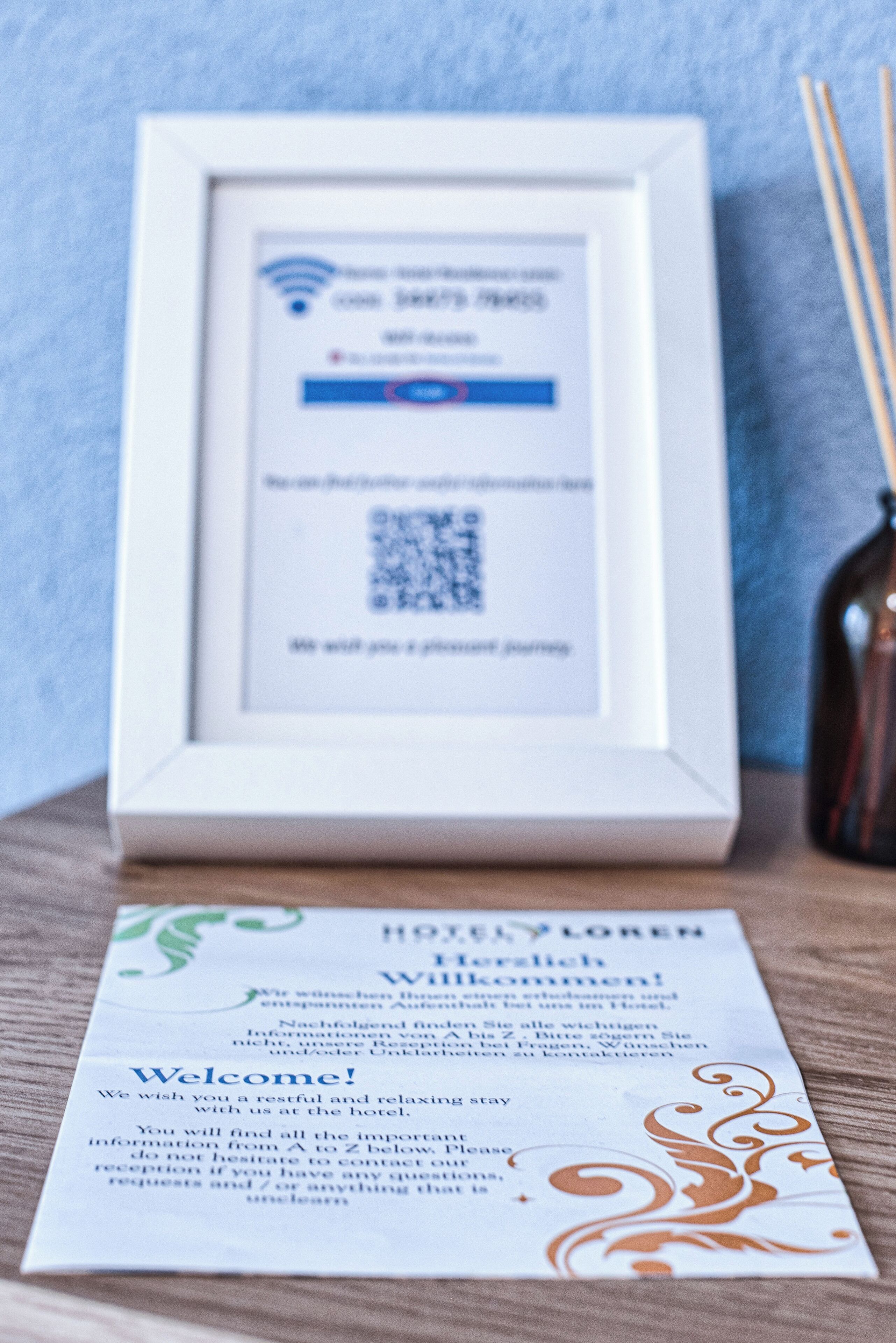 A framed QR code and a welcome card on a wooden surface.