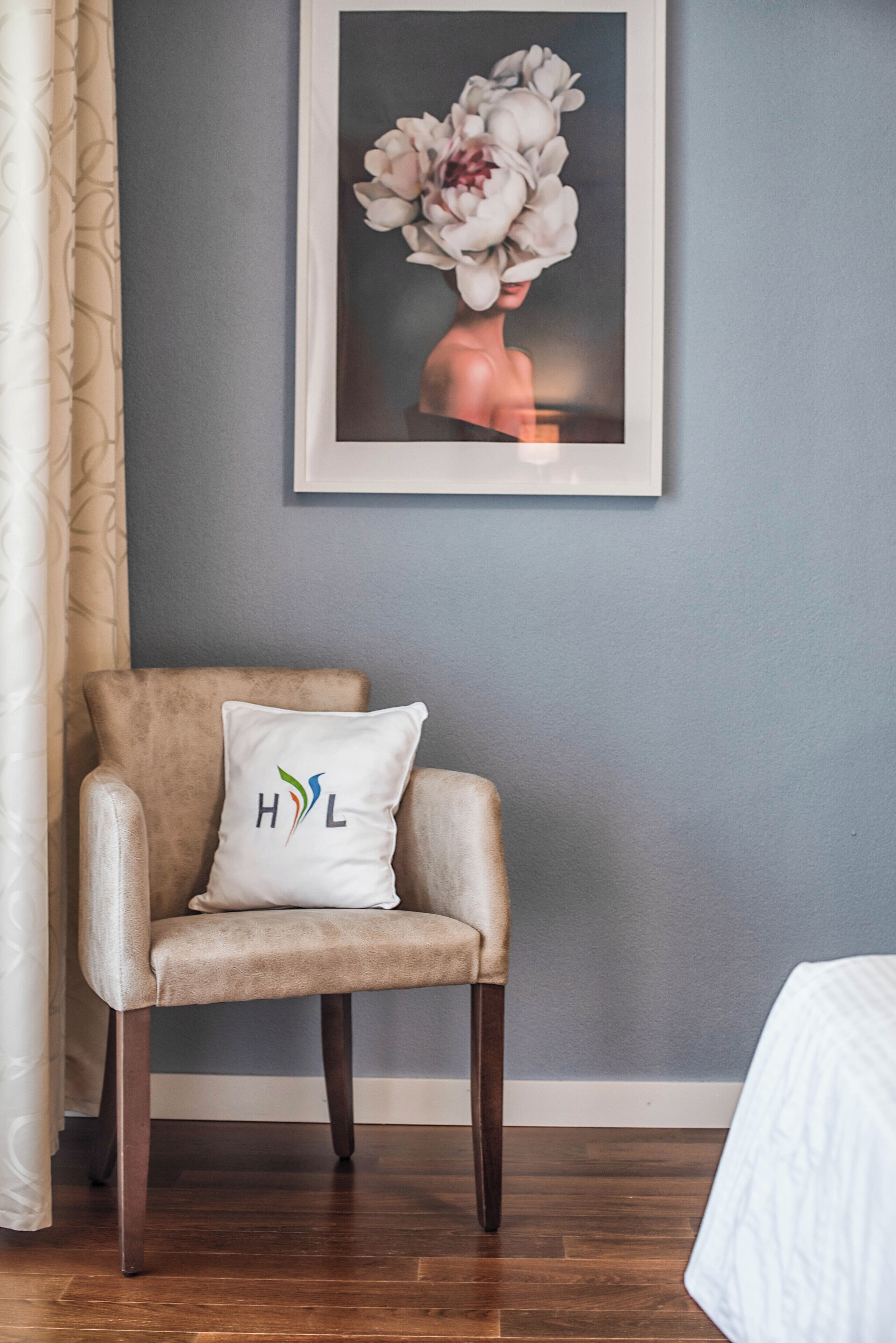 Una silla con un cojín que muestra un logotipo, una obra de arte floral enmarcada en la pared y un suelo de madera.