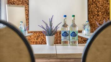 A conference table with two bottles of Arkina vodka, a potted lavender plant, and a whiteboard in a room with cork wall decor.
