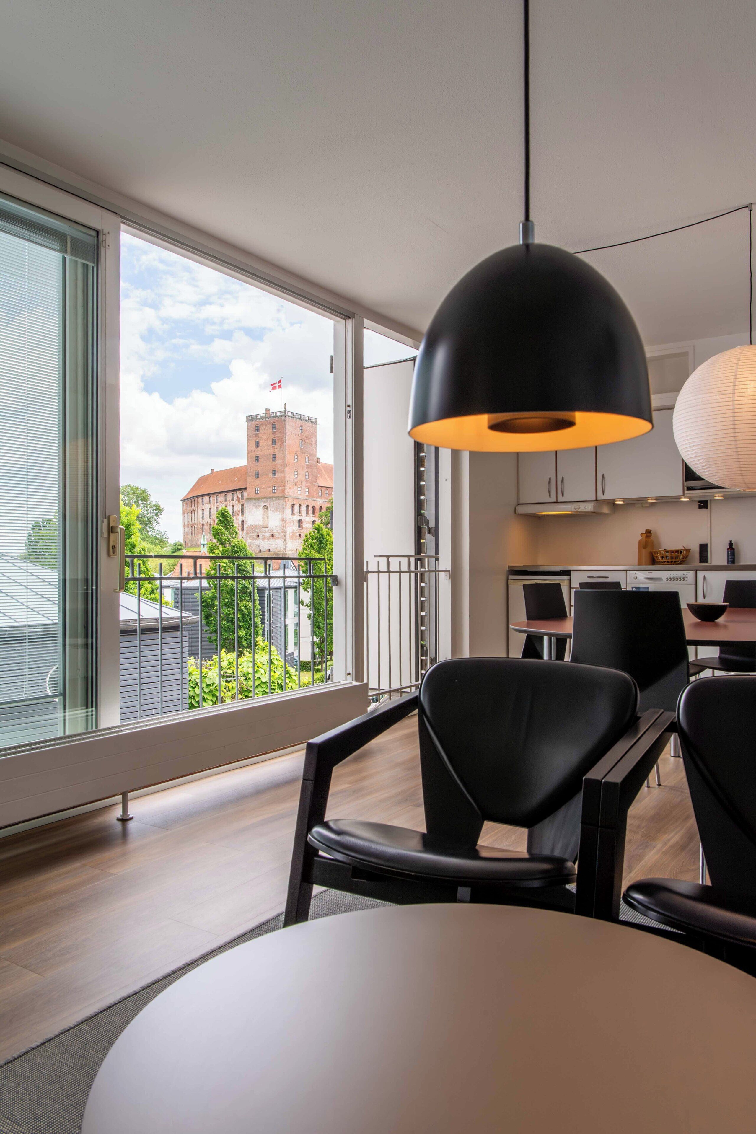 A modern kitchen with a dining area, large windows, and a view of a building.