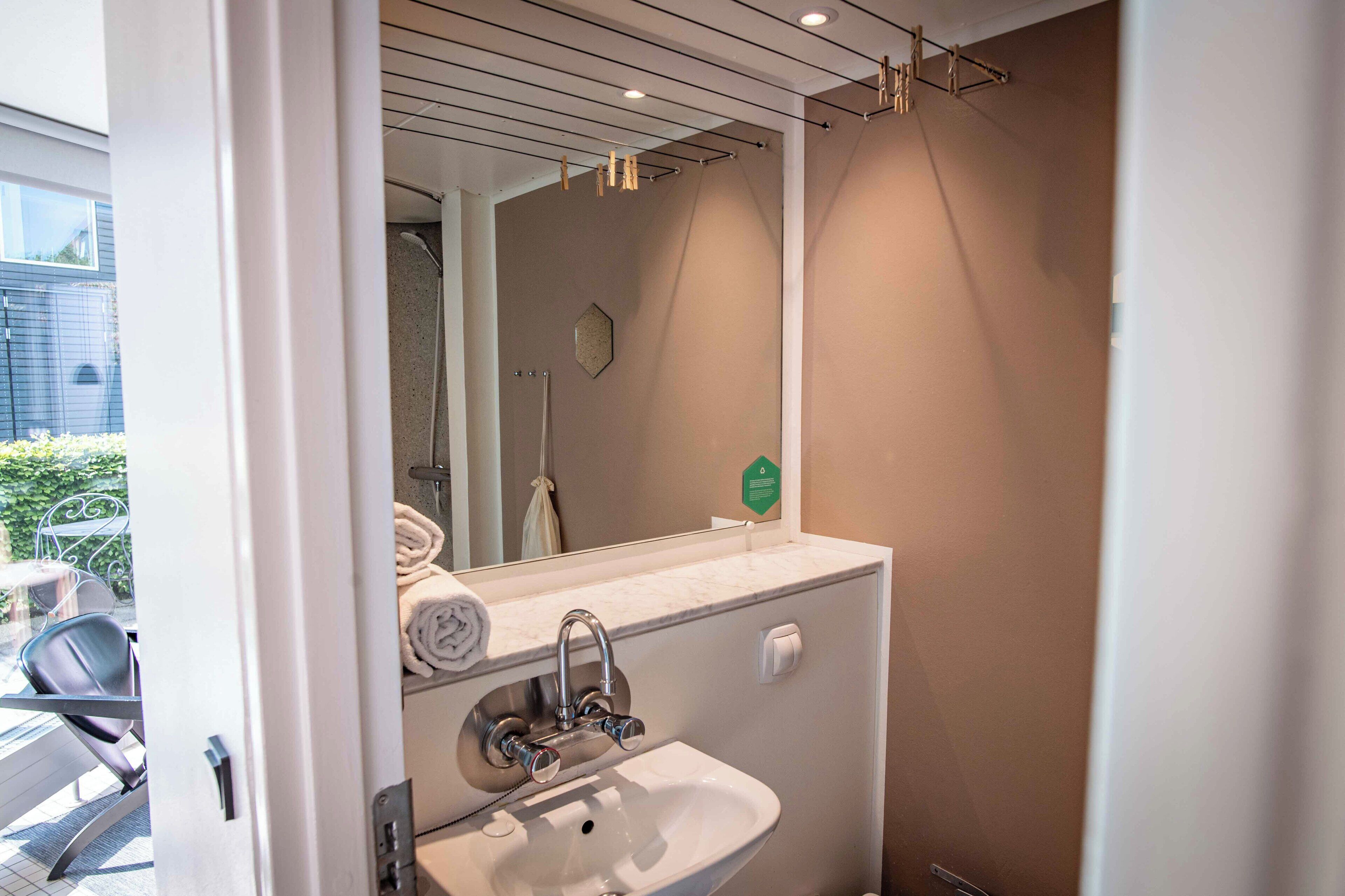 A modern bathroom with a sink, mirror, and towel rack.