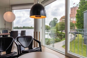 Una habitación moderna con un ventanal grande, una mesa con sillas y una lámpara colgante.