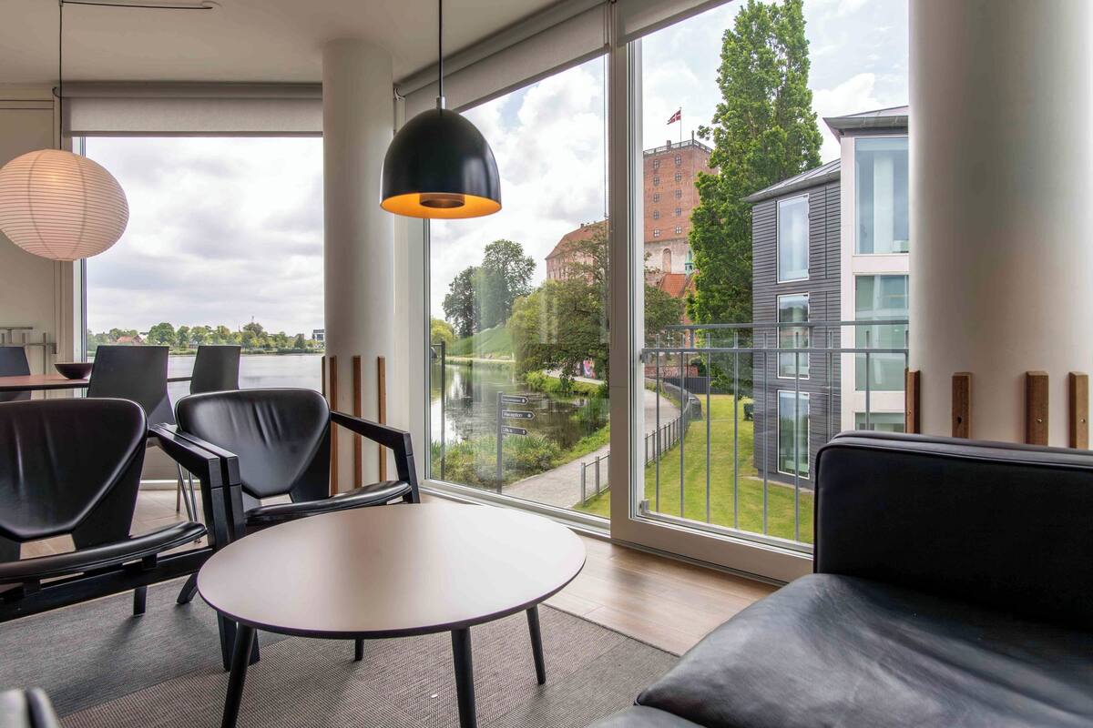 A modern interior with a large window, a round table, and black chairs.