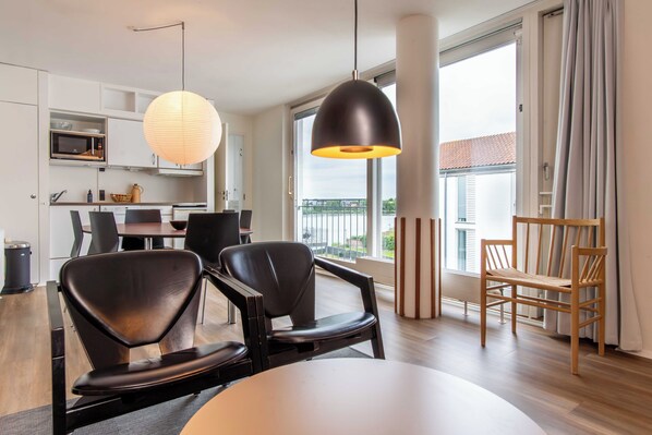 Una cocina moderna con microondas, mesa de comedor, sillas y un ventanal grande.