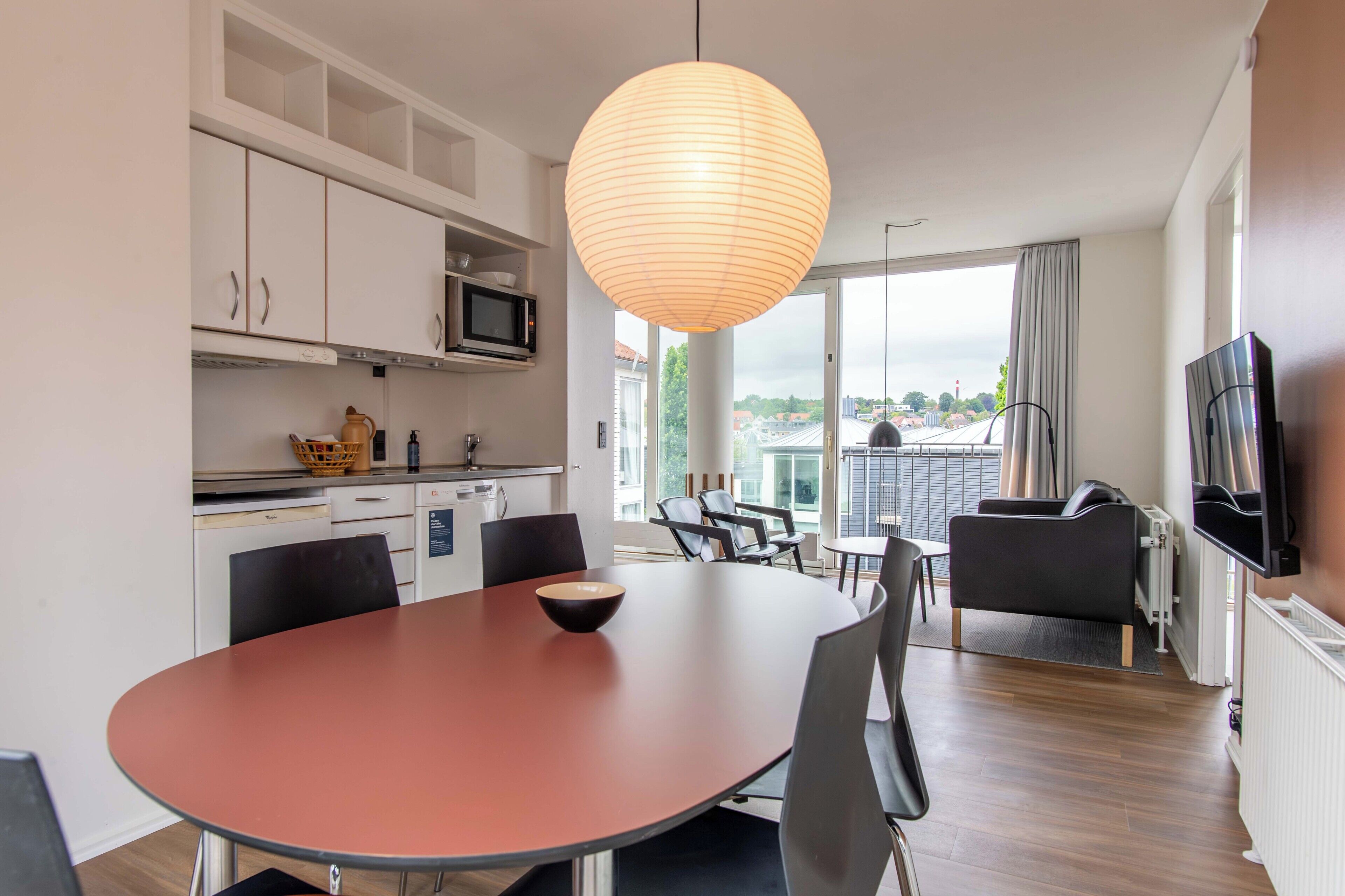 A modern kitchen with white cabinets, a microwave, and a dining area with a round table and chairs.