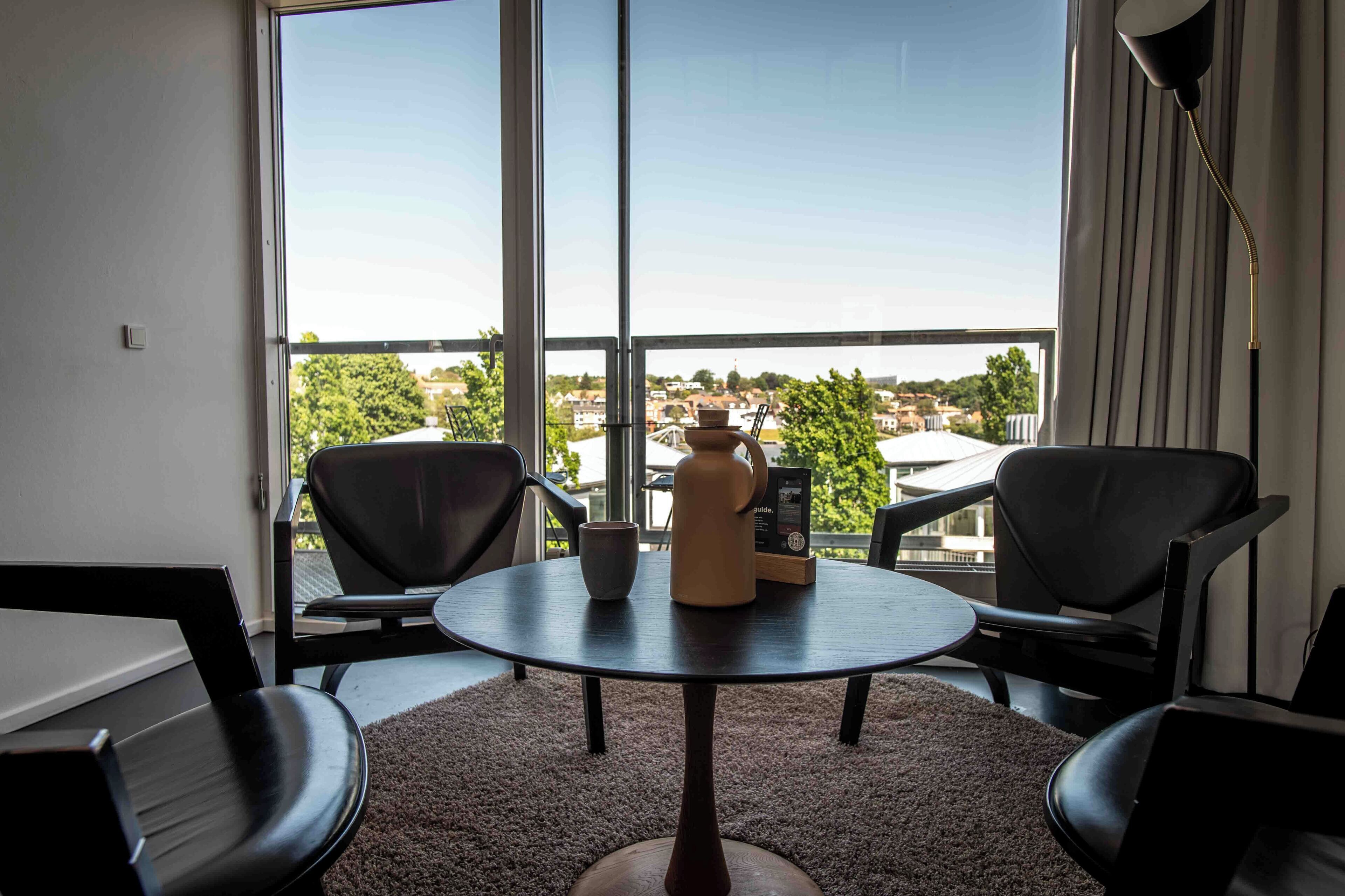 A room with a round table, two chairs, a vase, and a lamp.