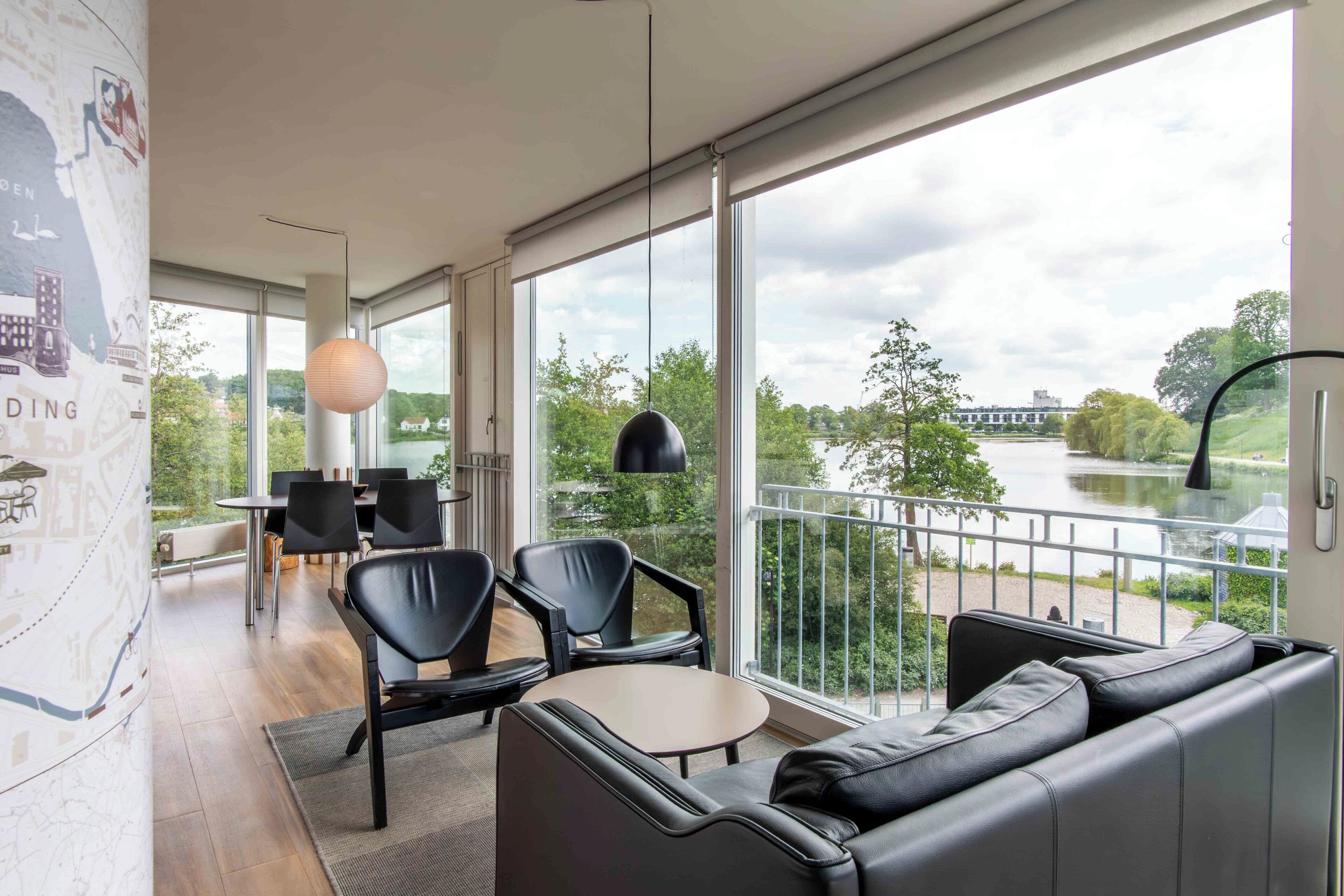 Een moderne kamer met een groot raam, een bank, stoelen, een tafel en een kaart aan de muur.