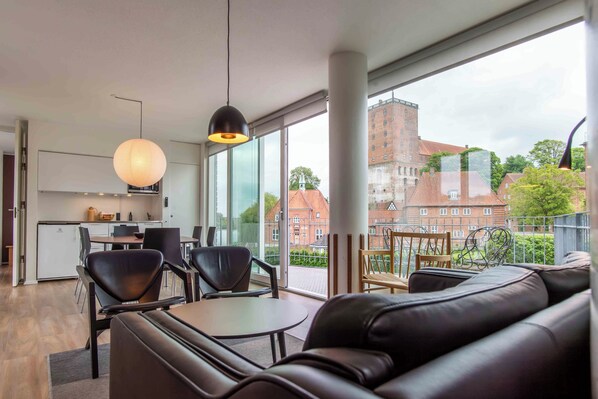 Een modern interieur met een bank, stoelen, een tafel en een keukenhoek.