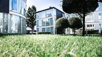 A modern building with large glass windows, a well-maintained lawn, and two neatly trimmed trees.