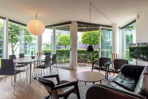 A modern interior with a dining area, seating, and large windows.