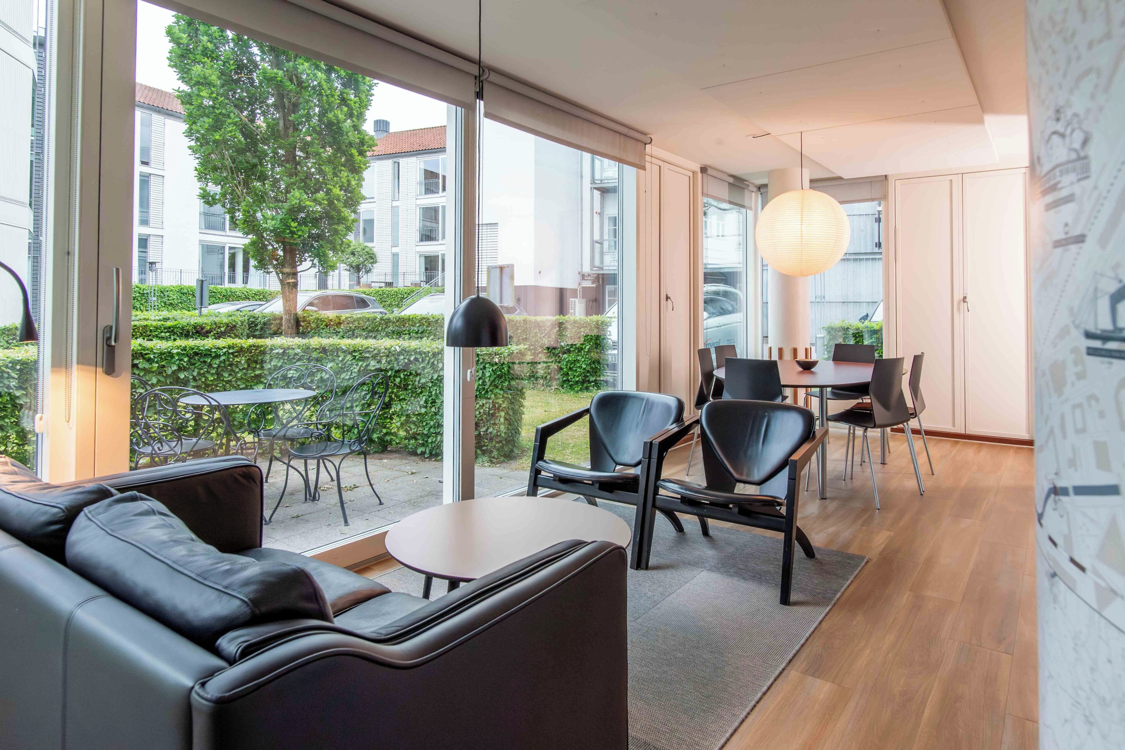 Ein modernes Interieur mit einer Couch, Sesseln, einem Tisch und Blick ins Freie.