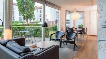 A modern interior with a sofa, chairs, a table, and a view of the outside.