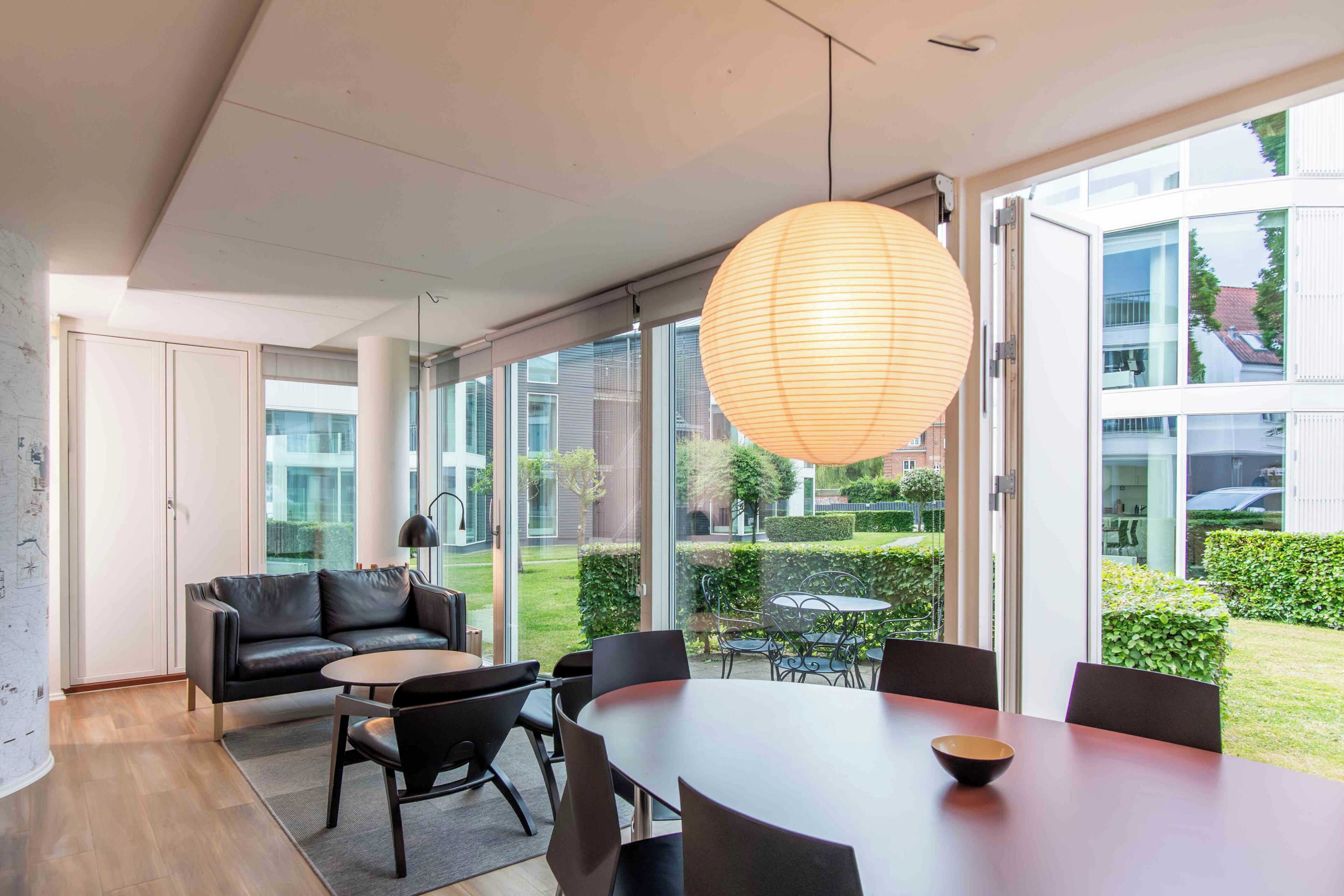 A modern interior with a dining area, a sofa, and large windows.