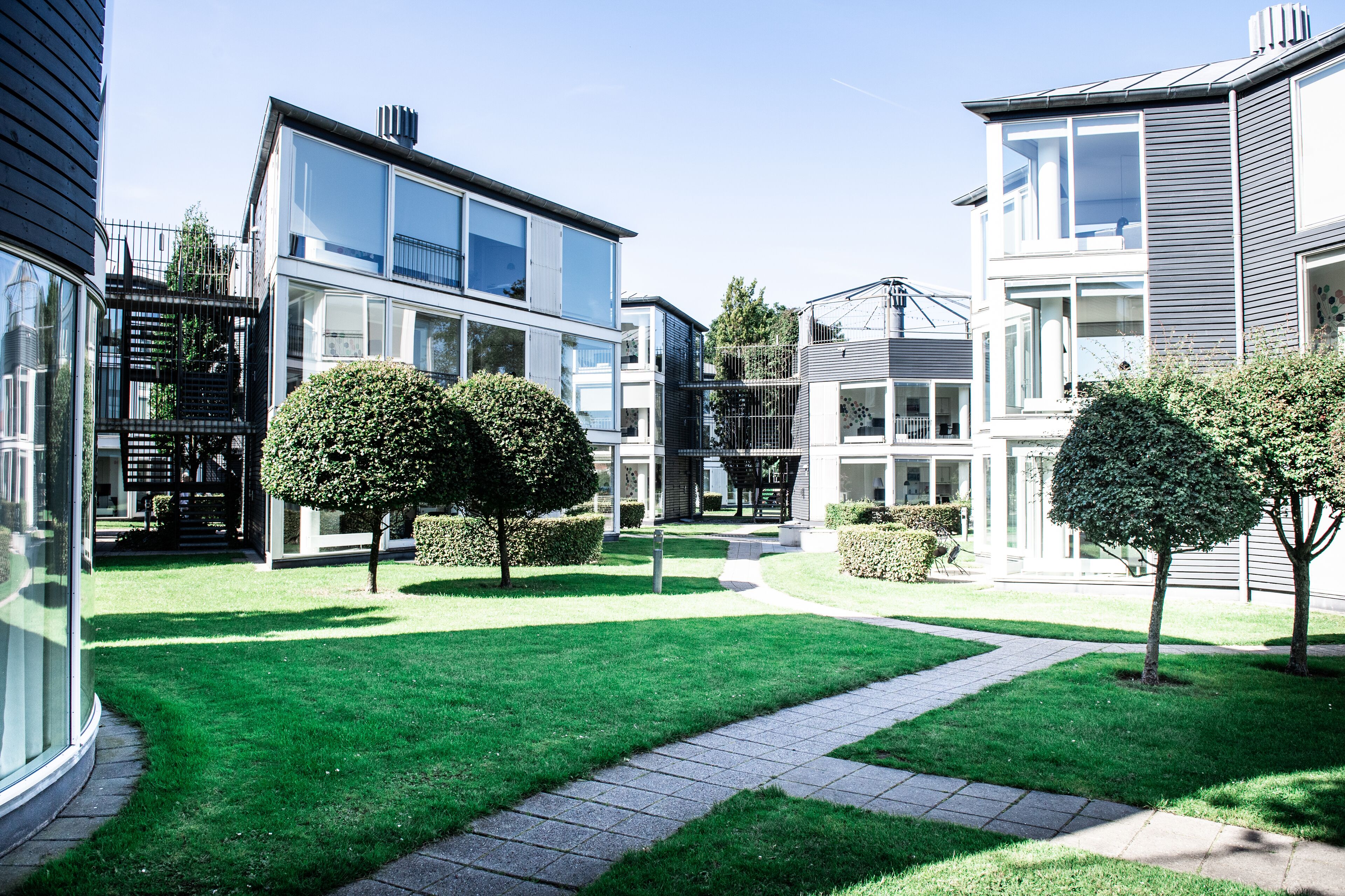 A modern residential complex with multiple two-story houses, a well-maintained lawn, and a paved walkway.