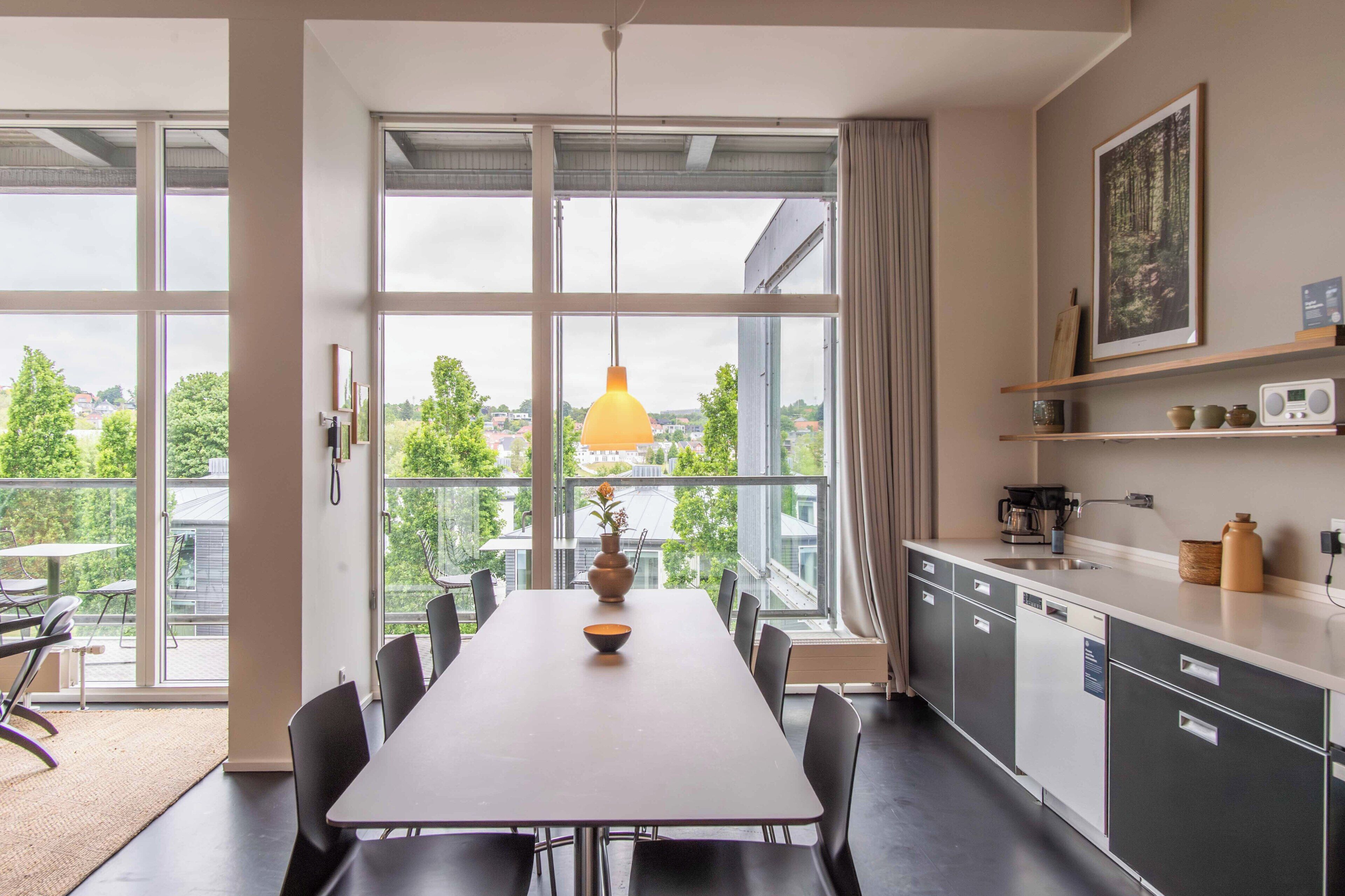 A modern kitchen with large windows, a dining area, and a view of the city.