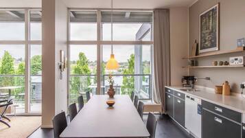 A modern kitchen with large windows, a dining area, and a view of the city.