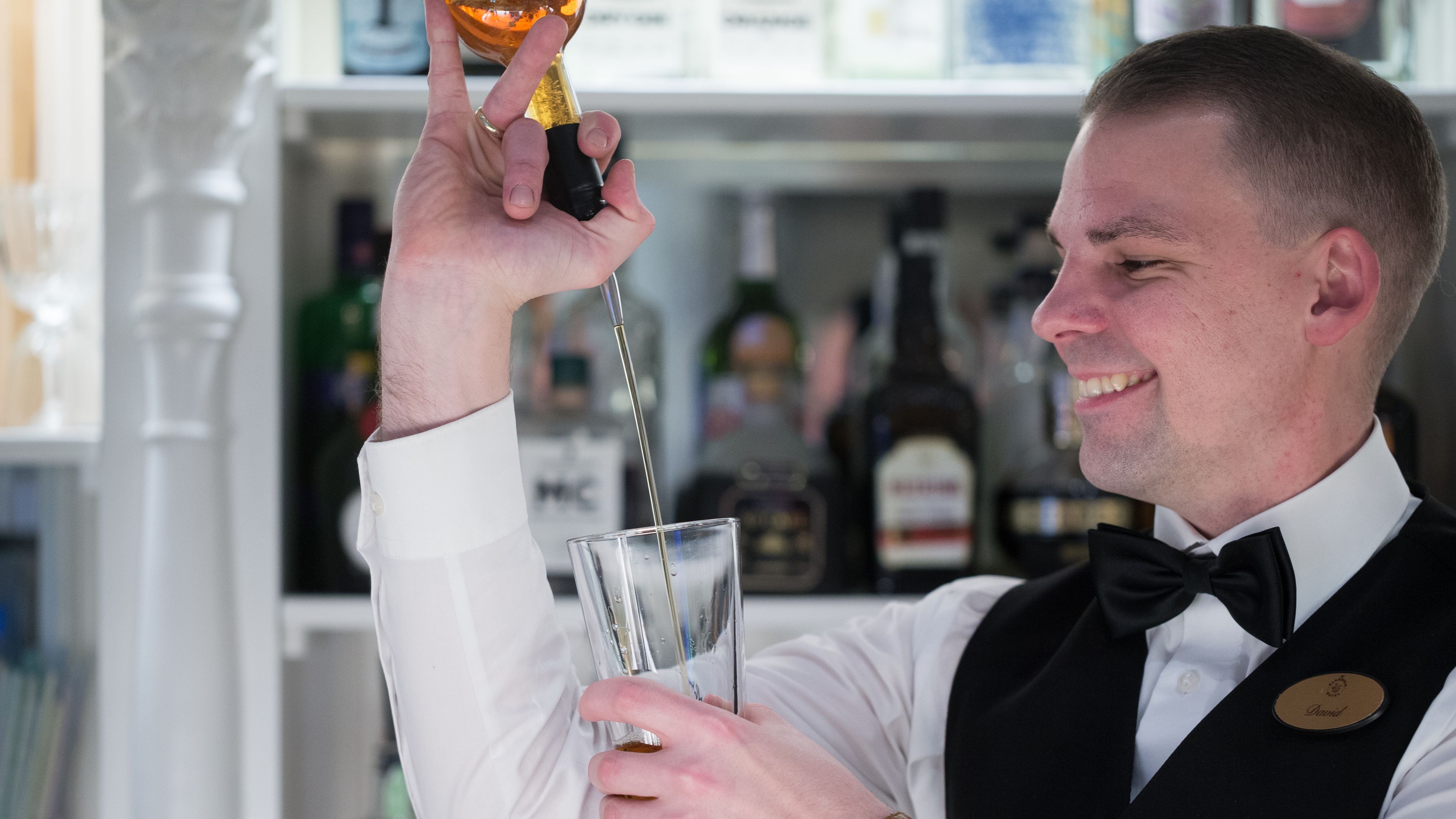 A bartender pouring a drink into a glass.