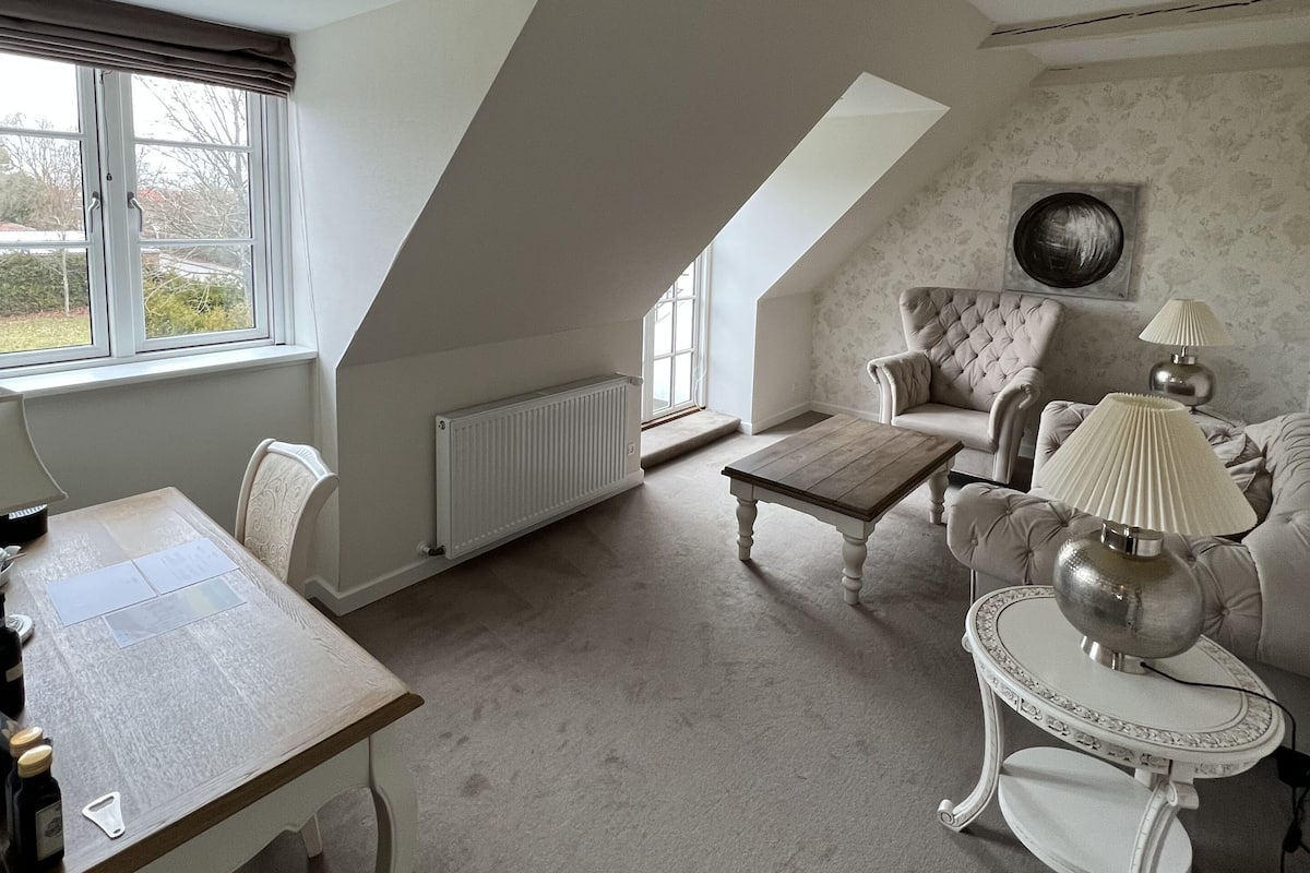 Une pièce spacieuse avec un plafond haut, une table à manger, un canapé et une lampe.