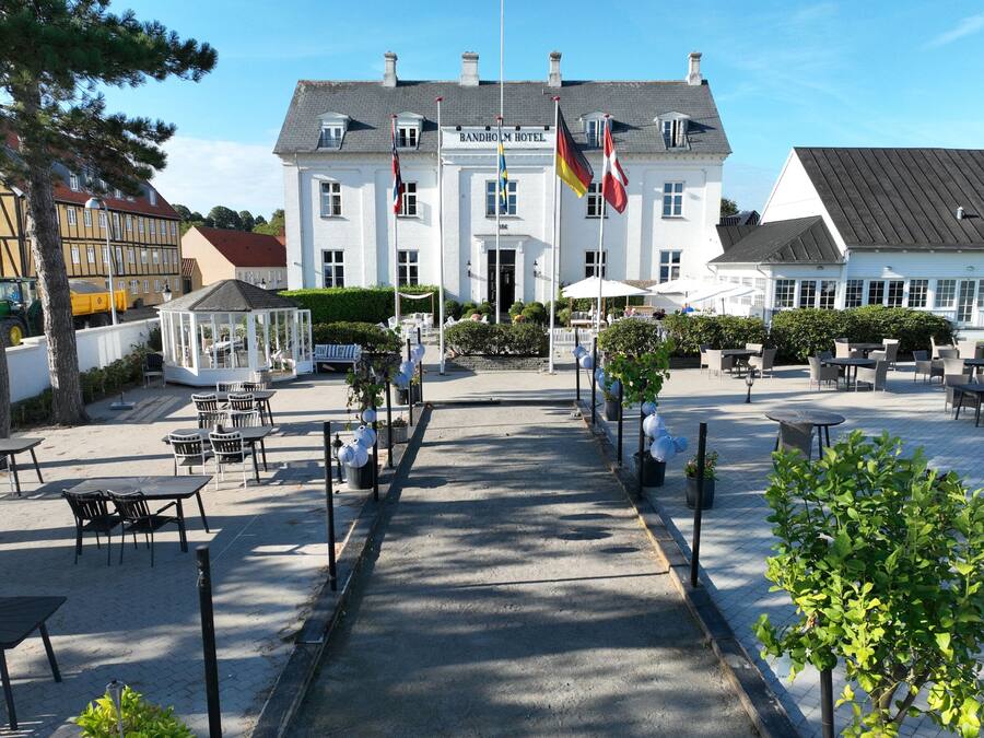 A hotel with a central courtyard, outdoor seating, and a flag display.