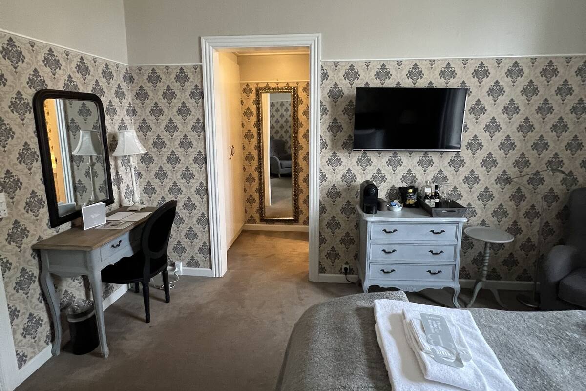 Une chambre d’hôtel équipée d’un lit, d’un bureau, d’une chaise, d’une commode et d’un téléviseur.