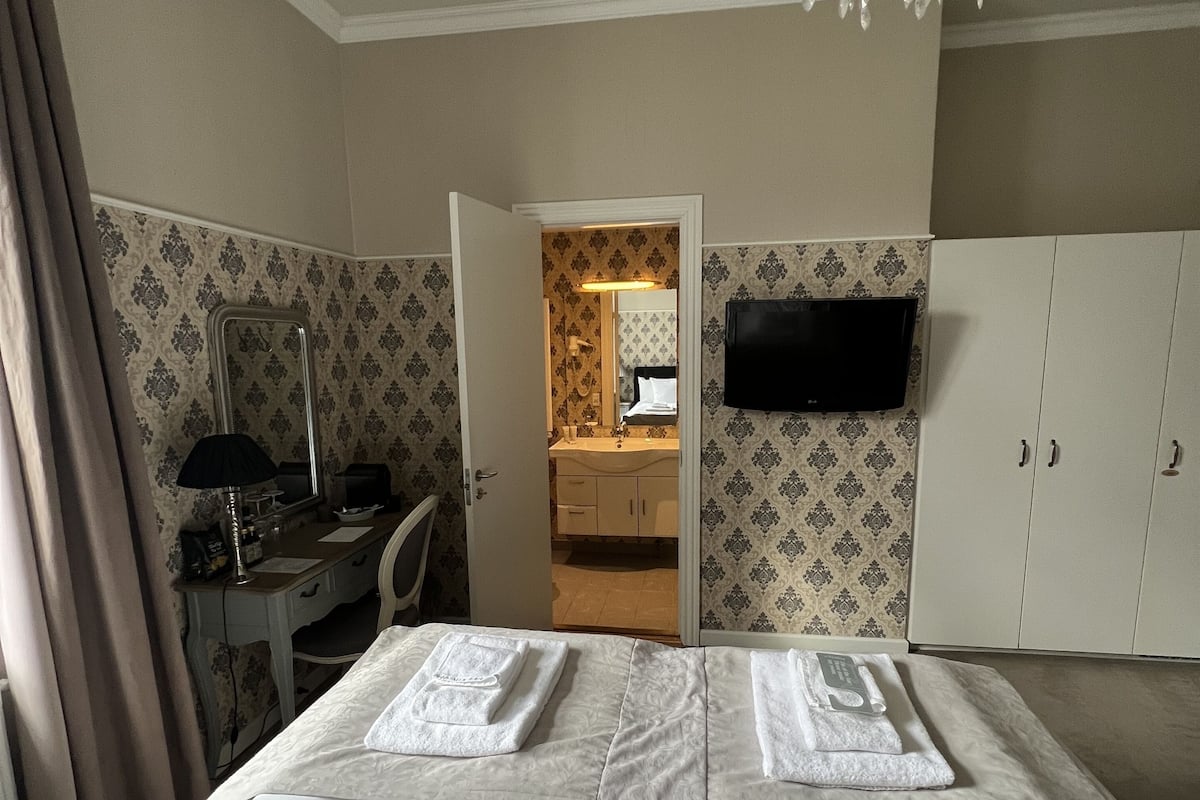 Une chambre d’hôtel équipée d’un lit, d’un bureau, d’une chaise, d’une télévision et d’une armoire.