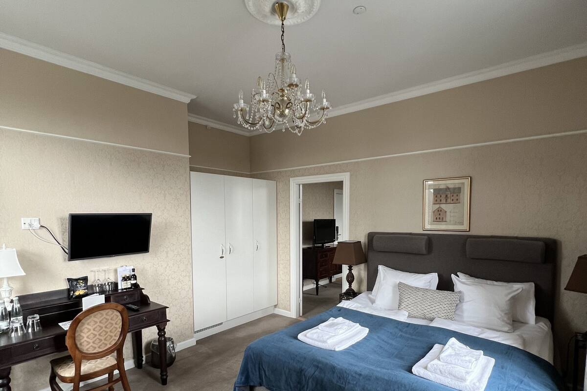Une chambre d’hôtel équipée d’un lit, d’un bureau, d’une chaise, d’une télévision et d’un lustre.