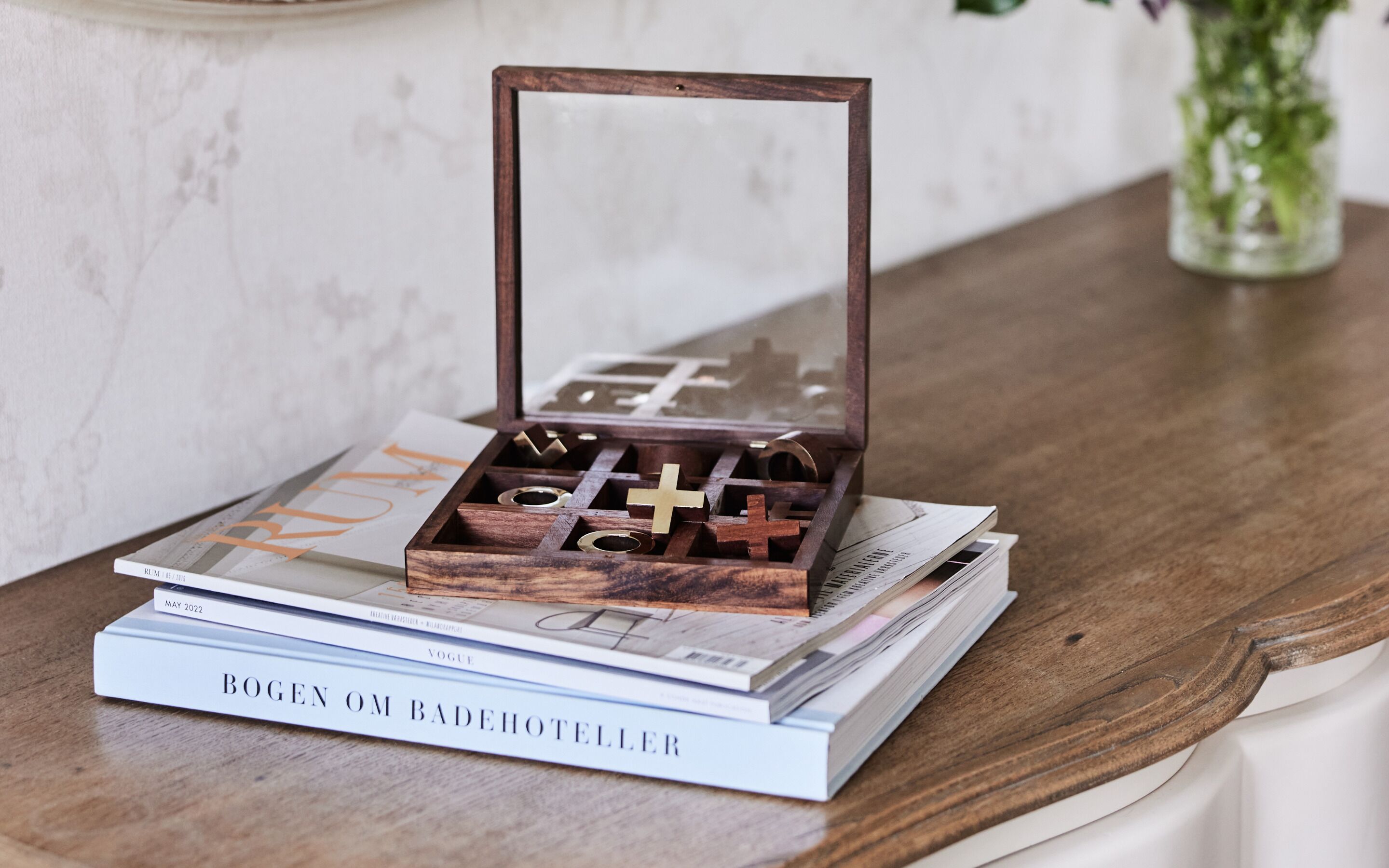 A wooden jewelry box with a mirror on top, placed on a stack of books.