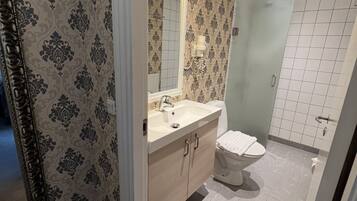A bathroom with a mirror, sink, and toilet.