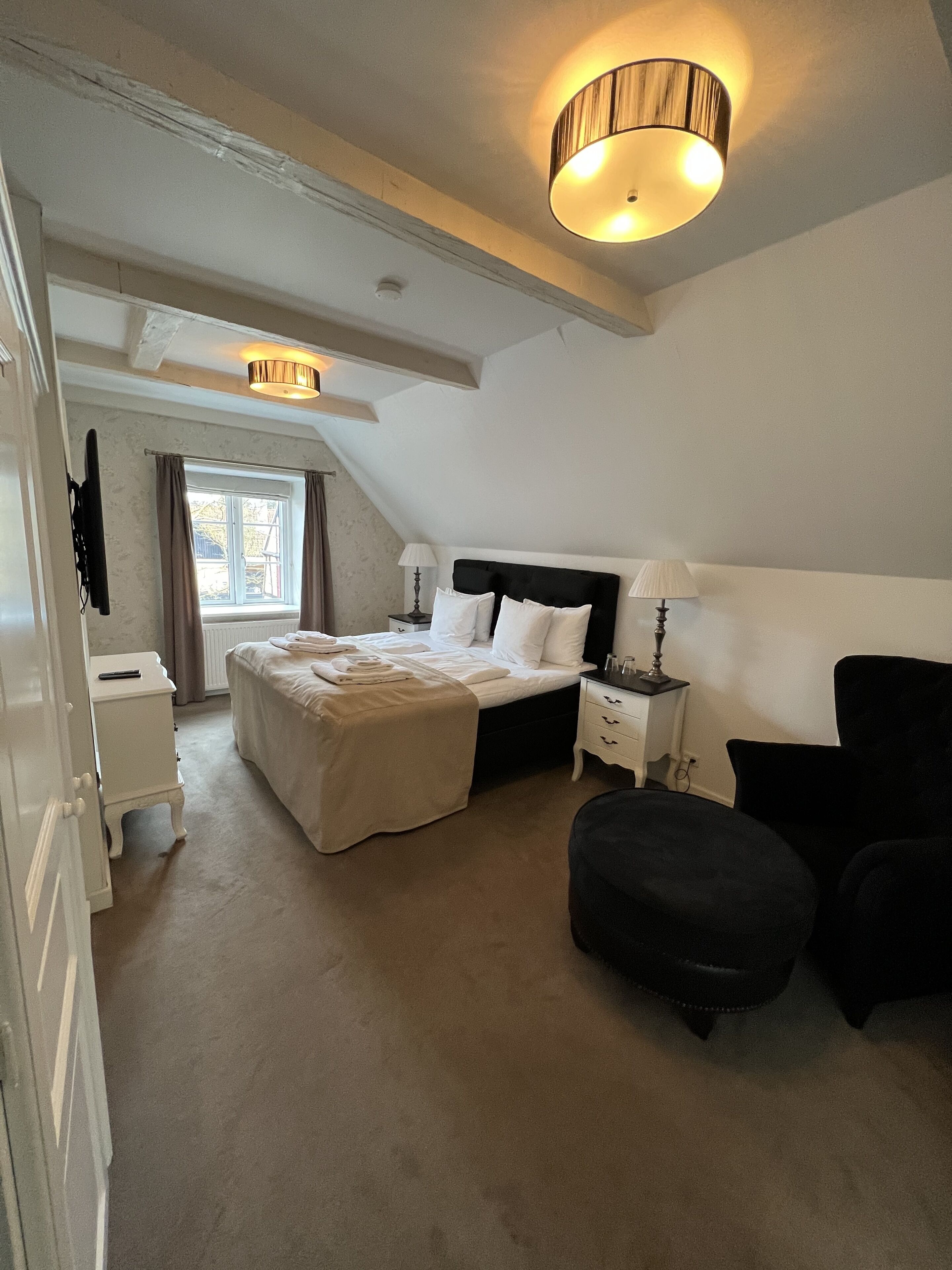 A bedroom with a bed, bedside tables, a lamp, a chair, and a window.
