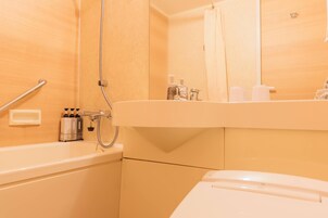 A bathroom with a bathtub, a shower, a toilet, and a sink with toiletries.