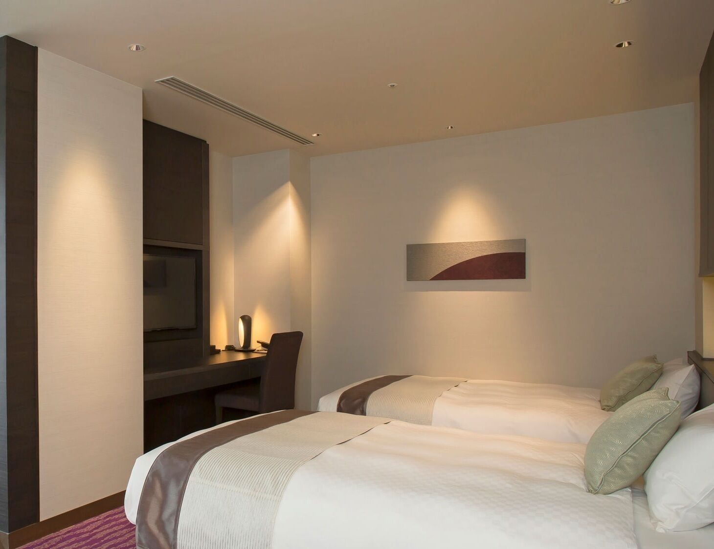 Une chambre d’hôtel avec deux lits, un bureau et une télévision.