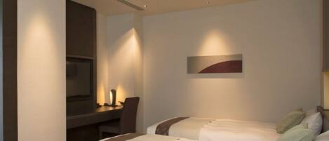 Habitación de hotel con dos camas, un escritorio y un televisor.