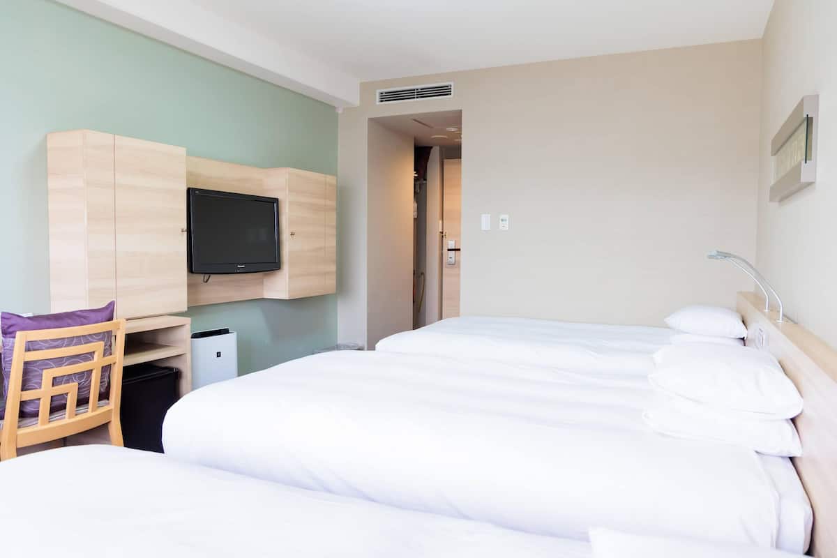 A hotel room with a bed, a TV, a desk, and a chair.