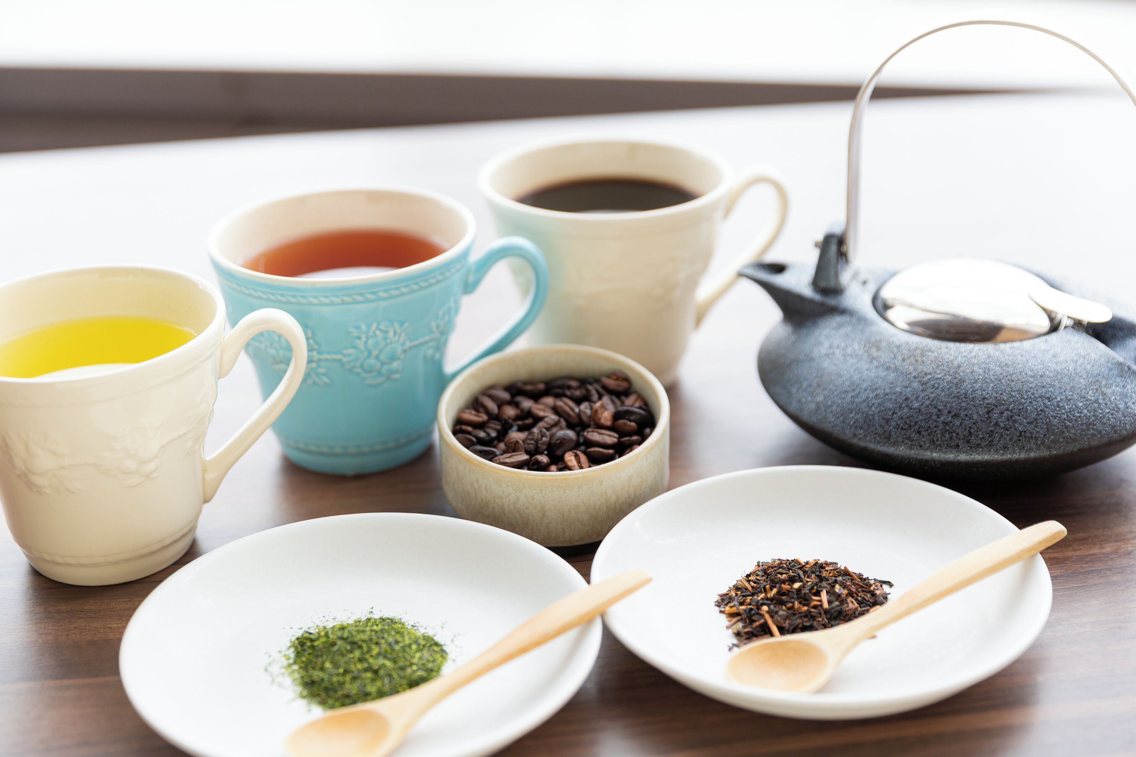 A table with various tea and coffee items including cups, a teapot, and spoons.